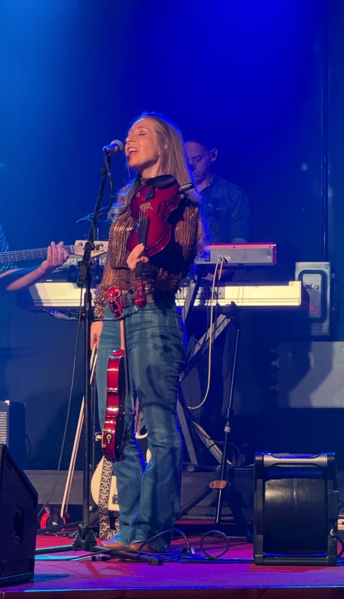 Melani X.O. singing live on stage while holding her violin